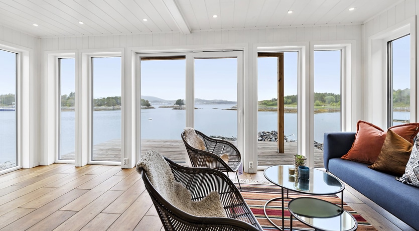 Interiør, Nærøysund rorbuer. Store vinduer ut mot sjøen. Sofakrok med to stoler.